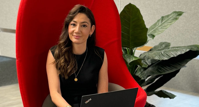 © Mainova Junge Businessfrau im schwarzen Kleid sitzt mit Laptop auf rotem Drehstuhl