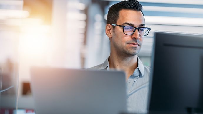 Ein mann mittleren Alters sitzt vor dem Bildschirm.