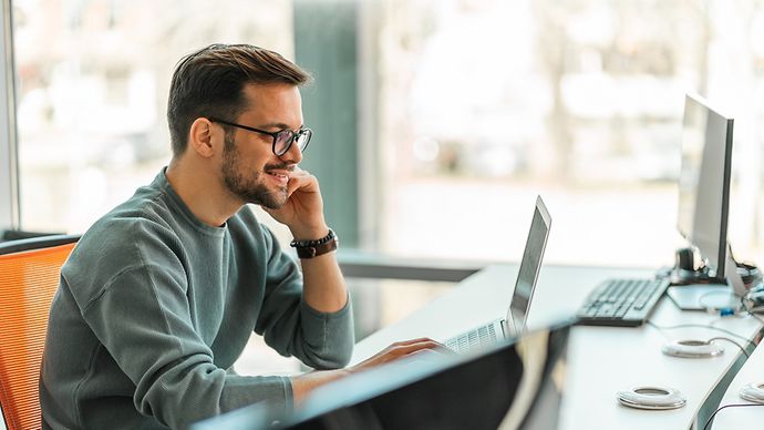 Ein junger Mann sitzt vor dem Laptop.