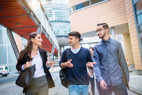 © Mainova/AndreForner Gruppe mit einer Studentin und zwei Studenten reden miteinander im Gehen.