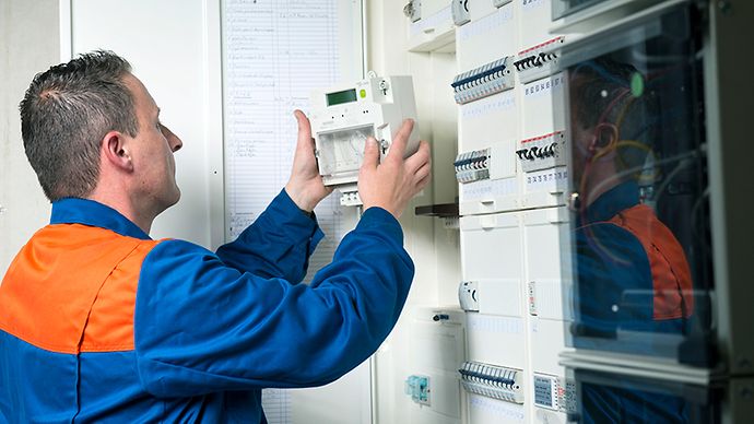 Ein Elektriker installiert einen Stromzähler in einem Schaltschrank.