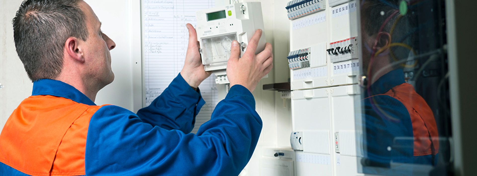 Ein Elektriker installiert einen Stromzähler in einem Schaltschrank.