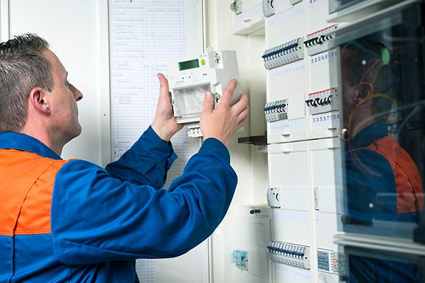 Ein Elektriker installiert einen Stromzähler in einem Schaltschrank.